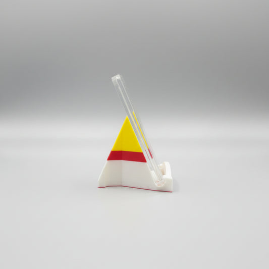 Colorful triangle-shaped object on a marble surface with a laptop in the background