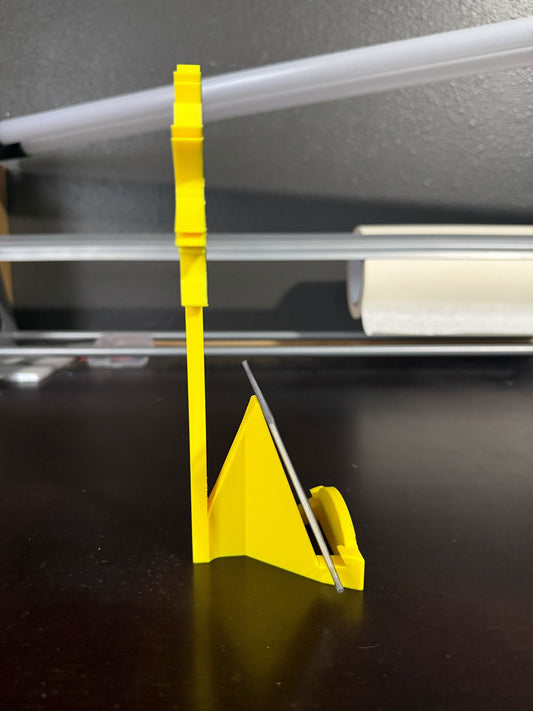 Yellow plastic tool with a metallic blade on a dark surface