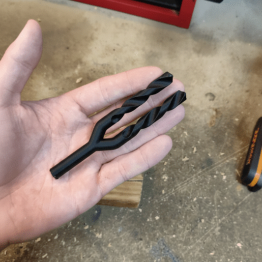 Hand holding a black metal tool against a concrete floor background