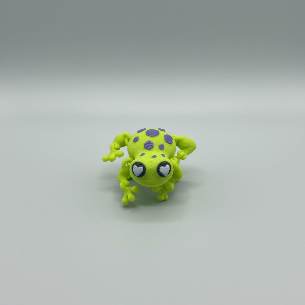 Green frog figurine with purple spots on a textured surface