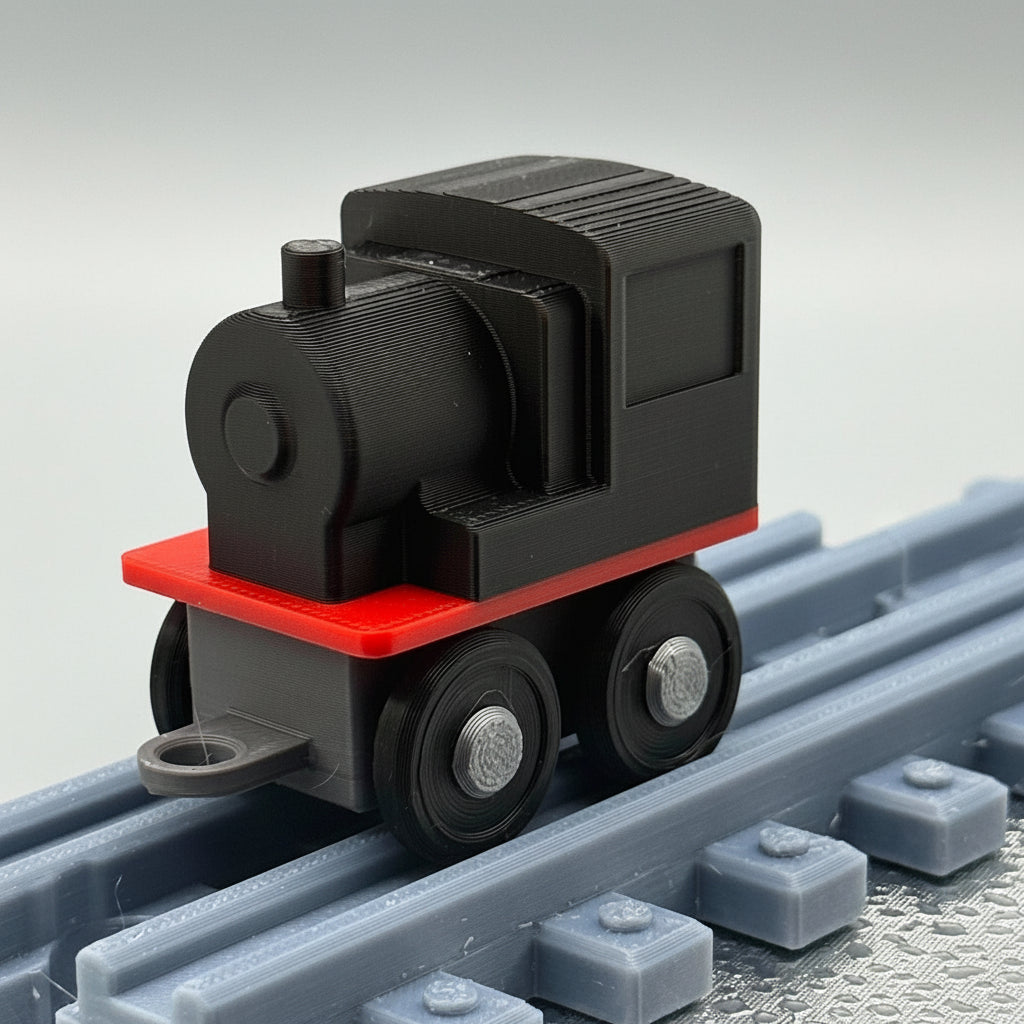 Black toy train engine with red front on a gray track against a textured gray background
