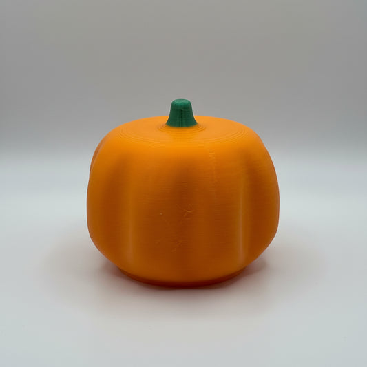 Orange pumpkin-shaped object on a white surface with a textured gray background