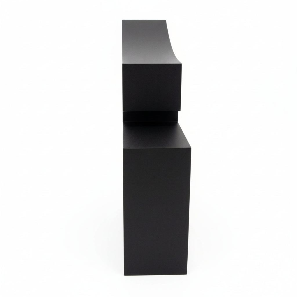 Black cube with a white device connected by a cable on a textured surface.