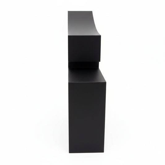 Black cube with a white device connected by a cable on a textured surface.