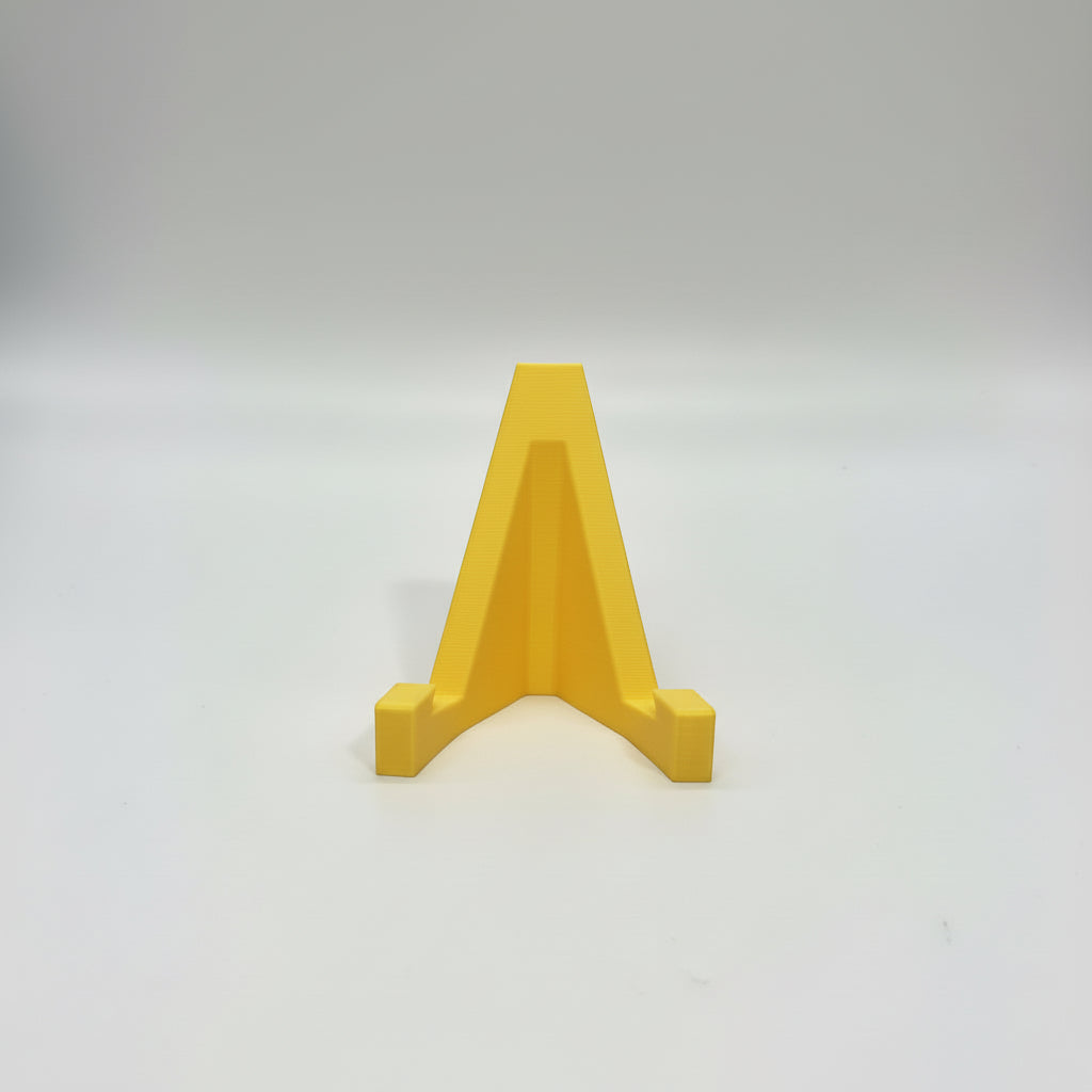 Hand holding a yellow A-shaped object against a gray background