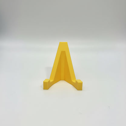 Hand holding a yellow A-shaped object against a gray background