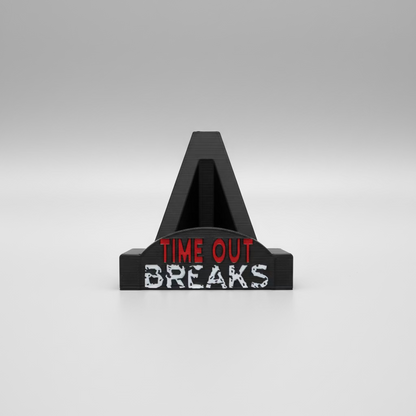Black clip with 'TIME OUT BREAKS' text held by a hand in front of a keyboard.