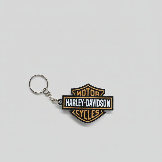 Harley-Davidson keychain on a dark surface with a 'Whatcha Printing' label in the background.