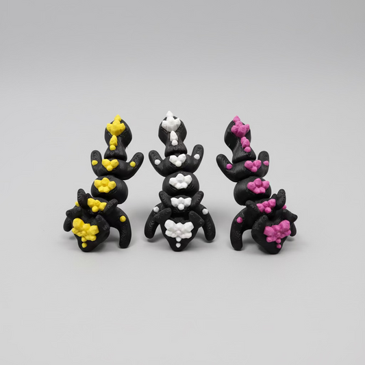 Three small figurines with colorful decorations on a carbon fiber background