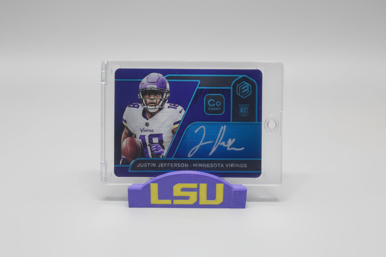 Football trading card of a player from LSU on a marble surface with sports memorabilia in the background.