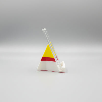 Colorful triangle-shaped object on a marble surface with a laptop in the background