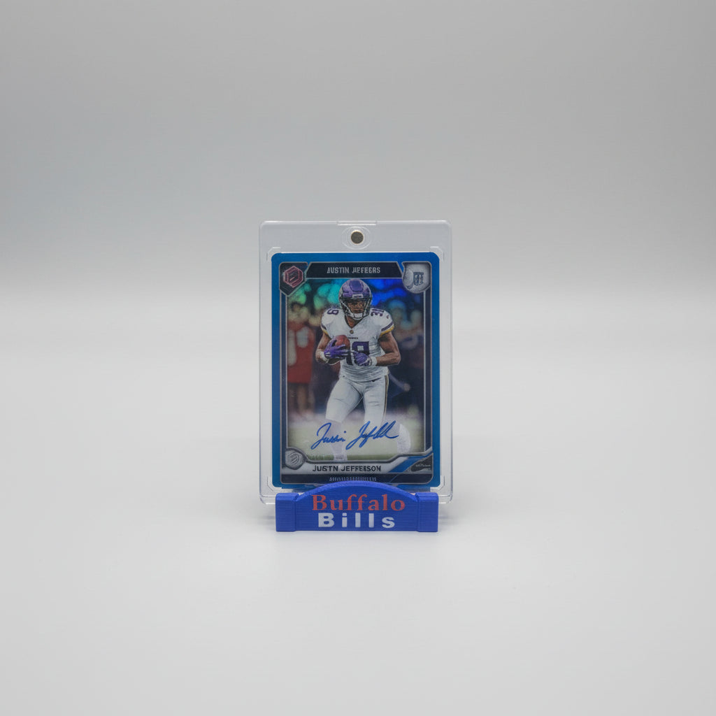 Football trading card of Justin Jefferson with a clear protective case on a marble surface, surrounded by other cards.