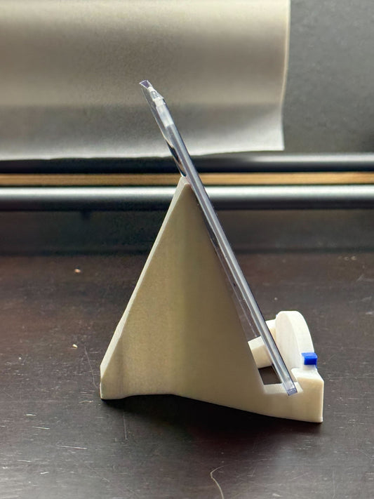 Clear plastic tool on a beige stand with a metallic background