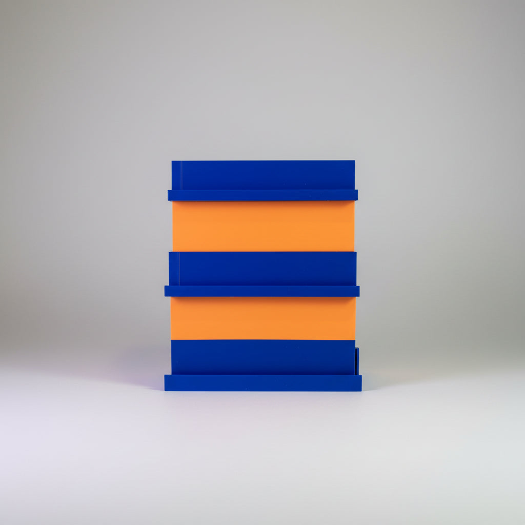 Stack of blue and orange blocks on a surface with a colorful background of cards or posters.