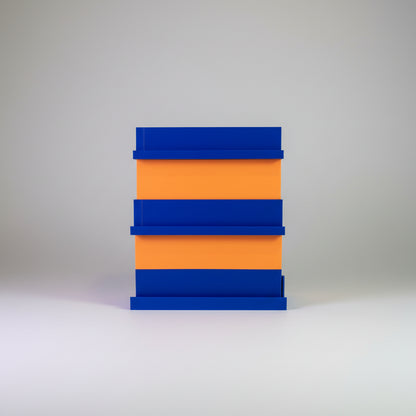 Stack of blue and orange blocks on a surface with a colorful background of cards or posters.