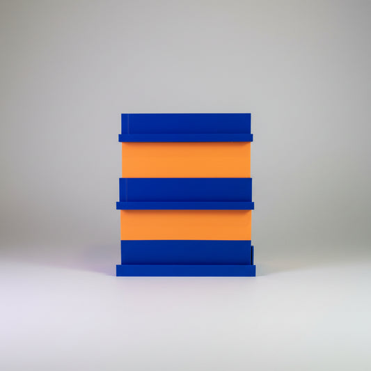 Stack of blue and orange blocks on a surface with a colorful background of cards or posters.