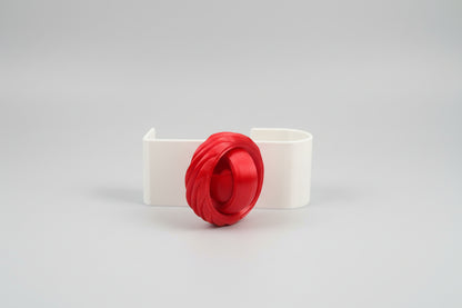 White decorative item with a red flower on a dark surface