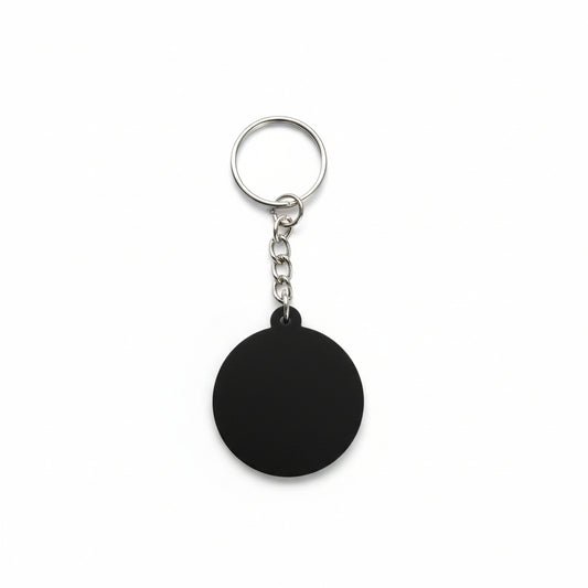 Black keychain with a round object on a textured surface