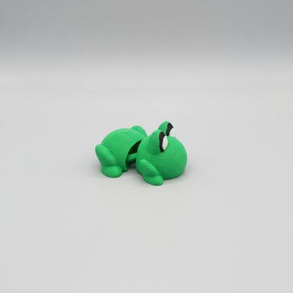 Green toy frog on a wooden surface