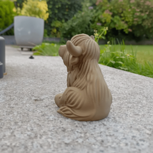 Terracotta sculpture of a bull on a stone surface with a garden background