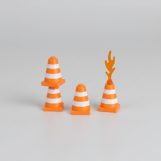 Toy traffic cones on a gray baseplate with a red toy vehicle in the background.