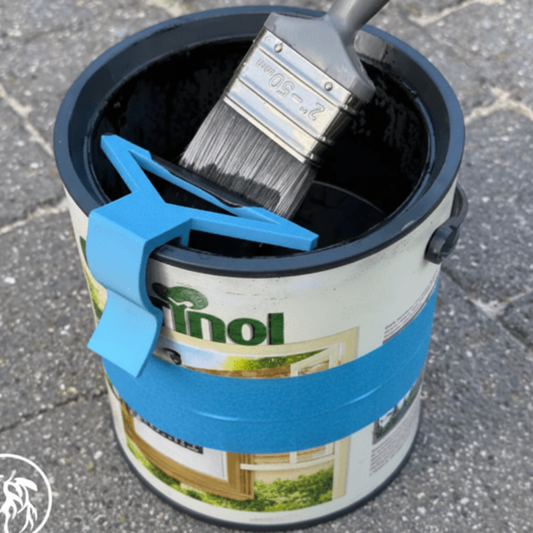 Paintbrush in a can of linseed oil with a blue clip on a textured surface