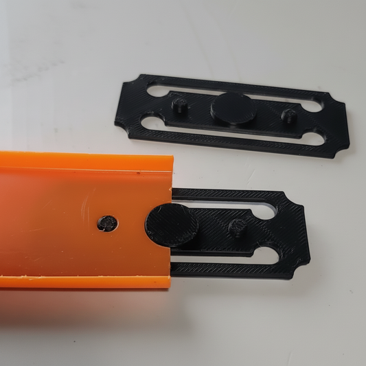Two metal brackets, one black and one orange, on a white background