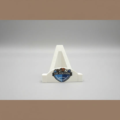 Small trophy with '225 Breakers' logo held in front of a larger logo on a wooden background