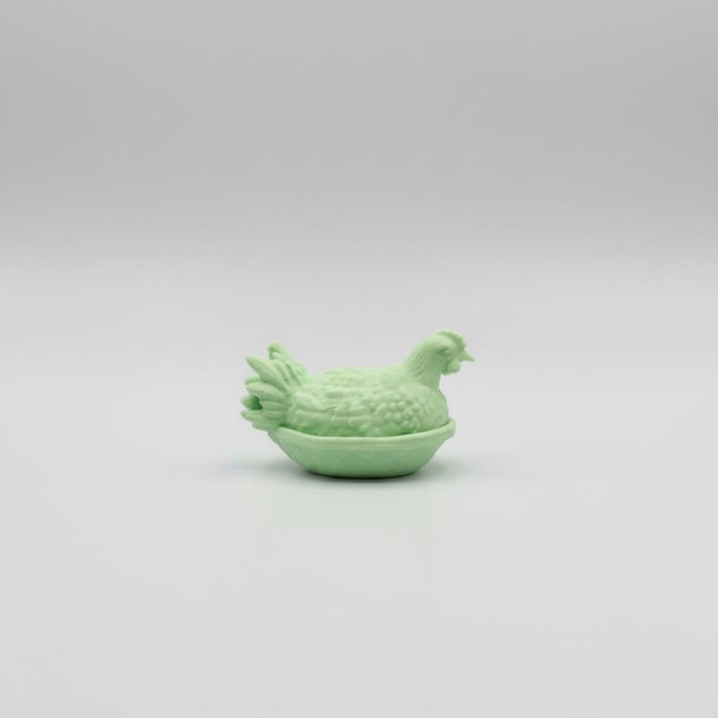 Green chicken-shaped object held in a hand against a neutral background