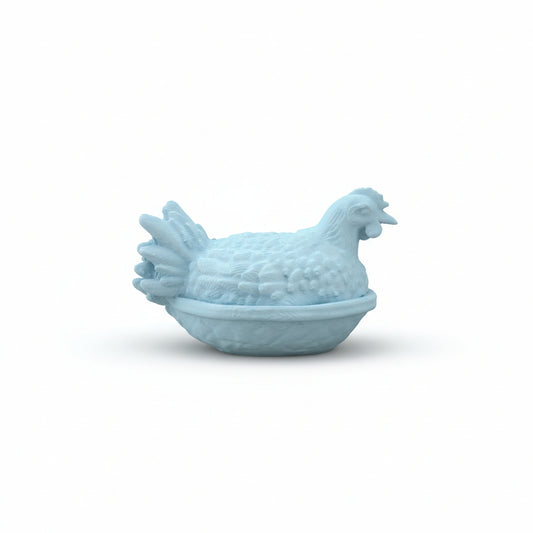 Small white ceramic chicken-shaped object held in a hand on a wooden surface