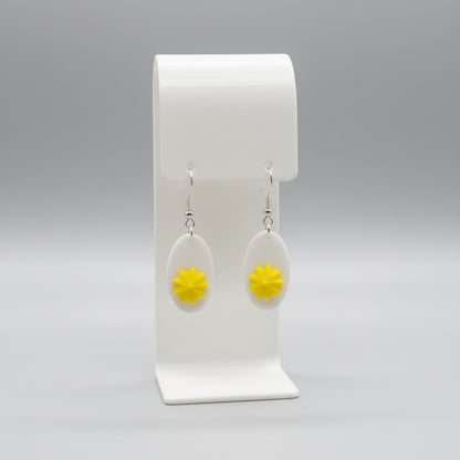 Earrings with yellow flower design on a white stand against a floral background