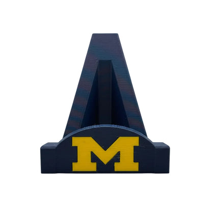 Blue letter 'A' with yellow 'M' on a white base against a textured gray background
