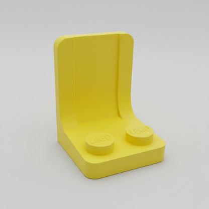 Yellow LEGO brick with two round studs on a textured surface
