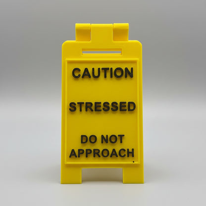 Yellow sign with text 'CAUTION STRESSED DO NOT APPROACH' on a textured background