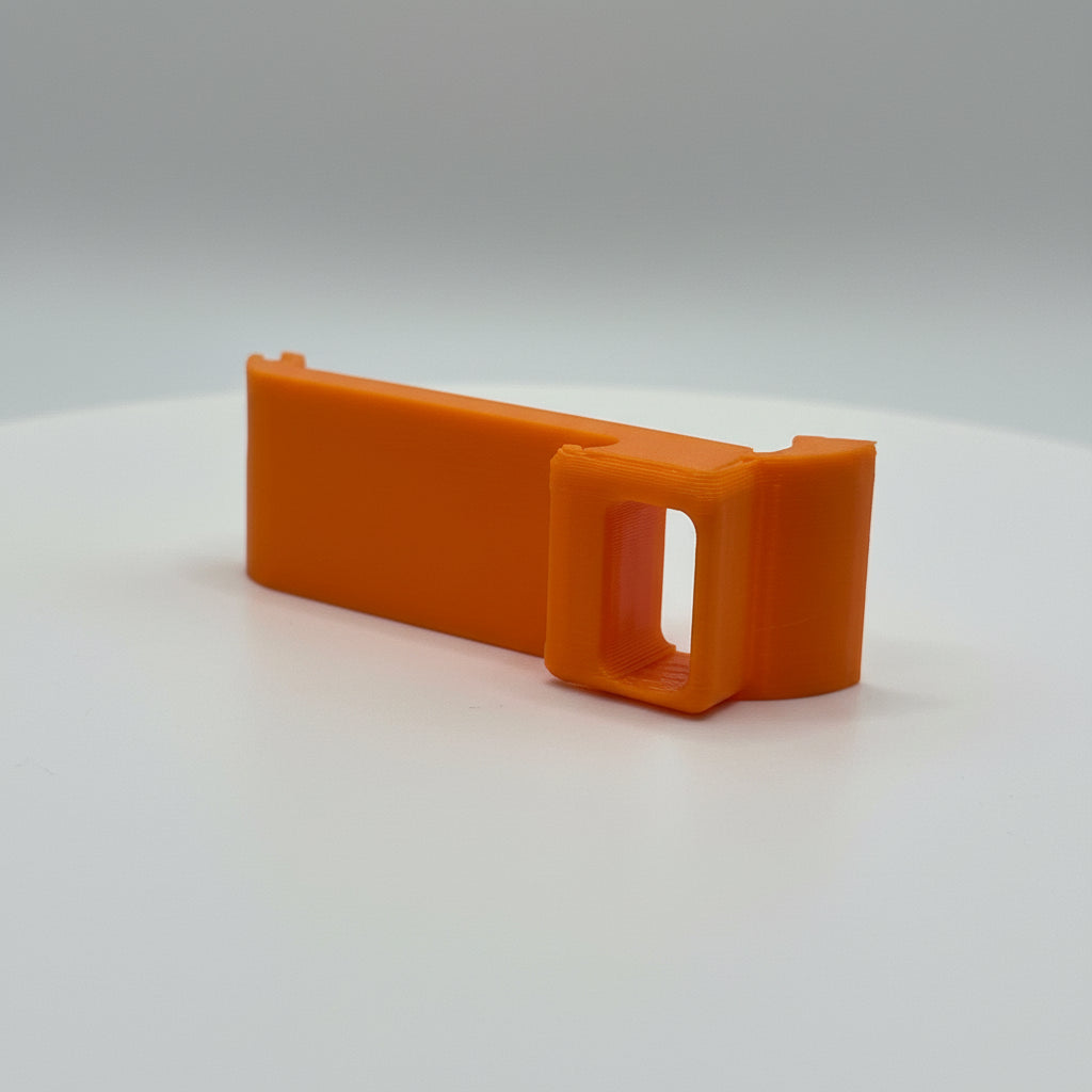 Orange plastic clip on a white surface with a textured gray background