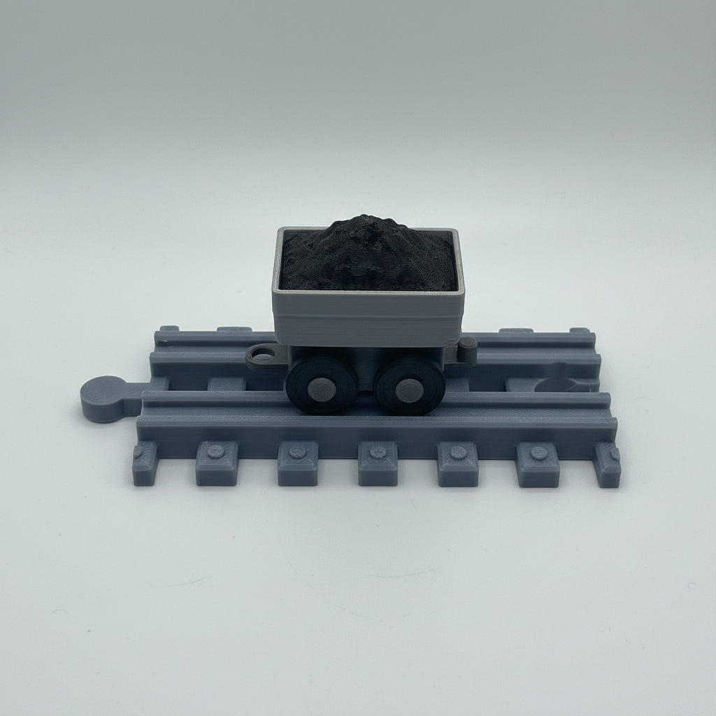 Toy train with a coal car on a textured metallic surface