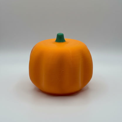 Orange pumpkin-shaped object on a white surface with a textured gray background