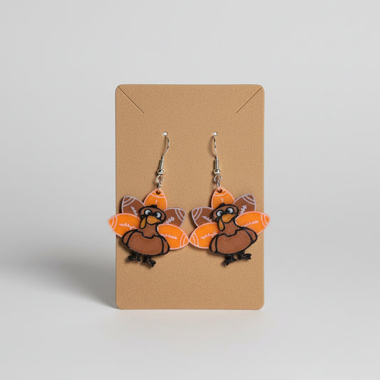 Turkey-shaped earrings on a brown card with a floral background