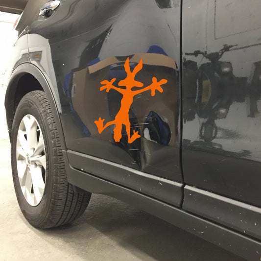 Car side with an orange decal of a stick figure with branches on a reflective surface.